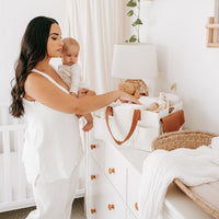 Mother holding her baby while organising her Bunnie Caddie Nappy Caddy