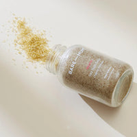 Bare Mum Sitz Bath Salt spilling out of a bottle on a beige background