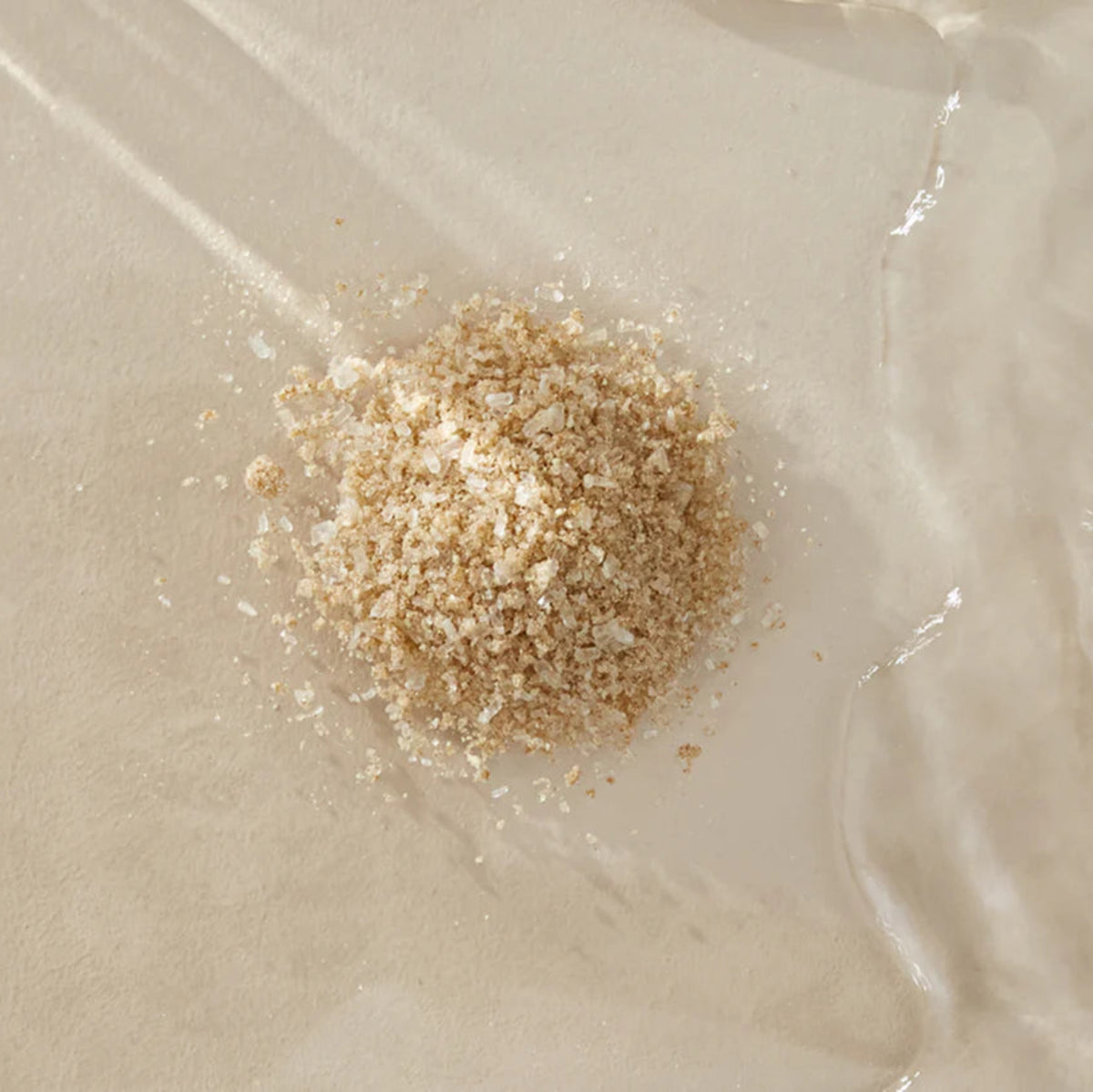 A small pile of Bare Mum Sitz Bath Salt on a textured beige surface