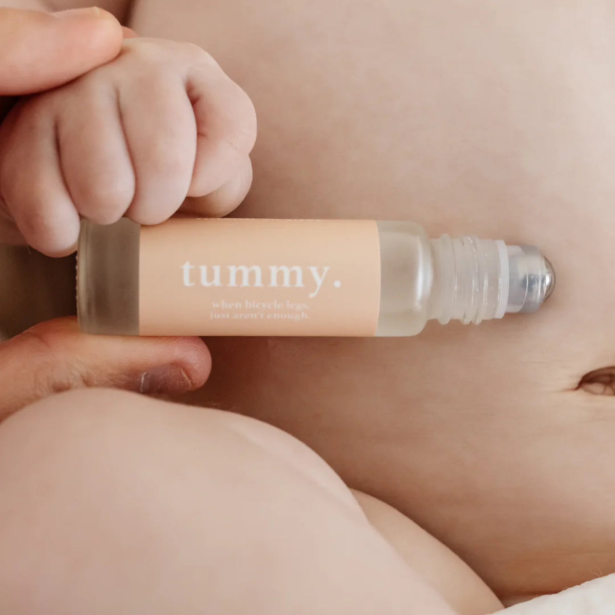 Roll-on essential oils for babies labelled 'tummy' held over a babies stomach.