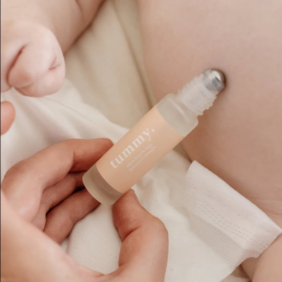 Roll-on essential oils for babies labelled "tummy" being held over a babys body