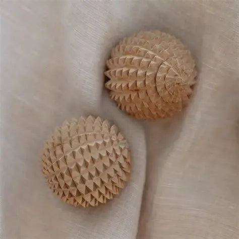 Two wooden textured birth weapon acupressure balls on a beige linen surface