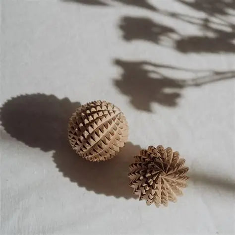 Two wooden birth weapon acupressure balls on a light surface with shadows.