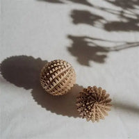 Two wooden birth weapon acupressure balls on a light surface with shadows.