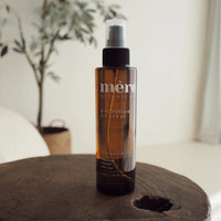 Bottle of Mere Botanicals Magnesium Spray on a wooden surface with a blurred background