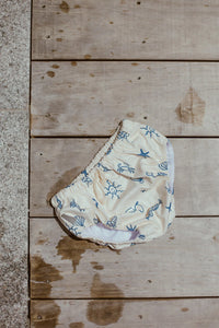 white reusable swim nappy with blue patterns on a wooden surface