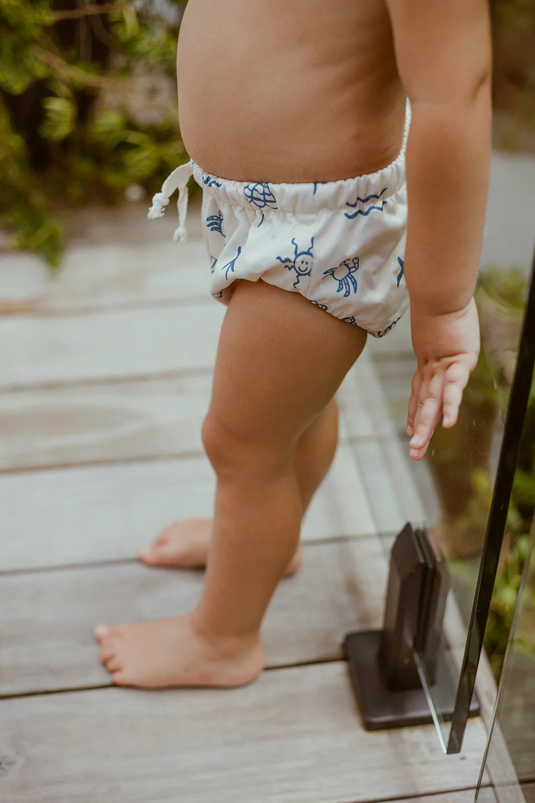 Child wearing a reusable swim nappy on a wooden deck