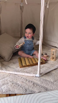 A video of a baby playing on a Qtoys bamboo xylophone while sitting inside a Henlee play tent.