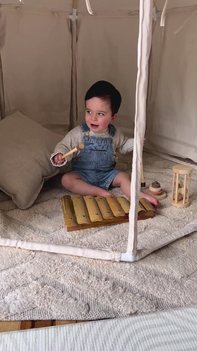 A video of a baby playing on a Qtoys bamboo xylophone while sitting inside a Henlee play tent.