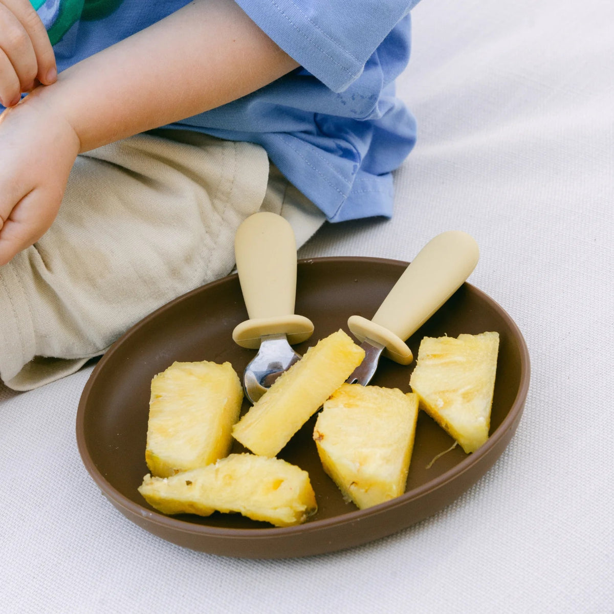 Rommer kids cutlery on a silicone plate with sliced pineapple.