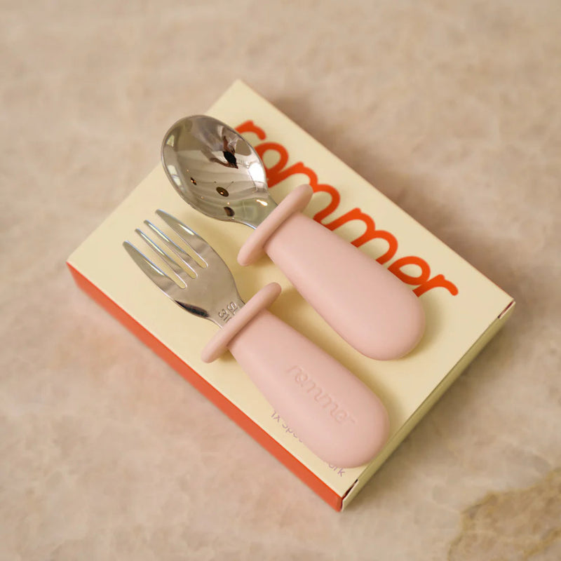 Pink kids cutlery set on a beige benchtop with Rommer packaging