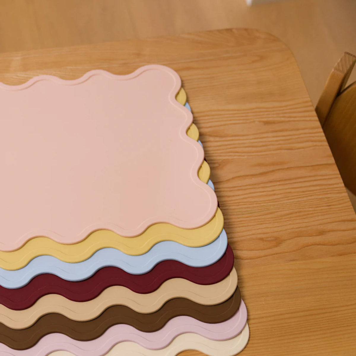A flatlay of Rommer silicone placemats on a wooden bench