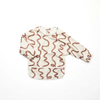 Rommer smock bib with brown wavy pattern on a white background