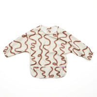 Rommer smock bib with brown wavy pattern on a white background