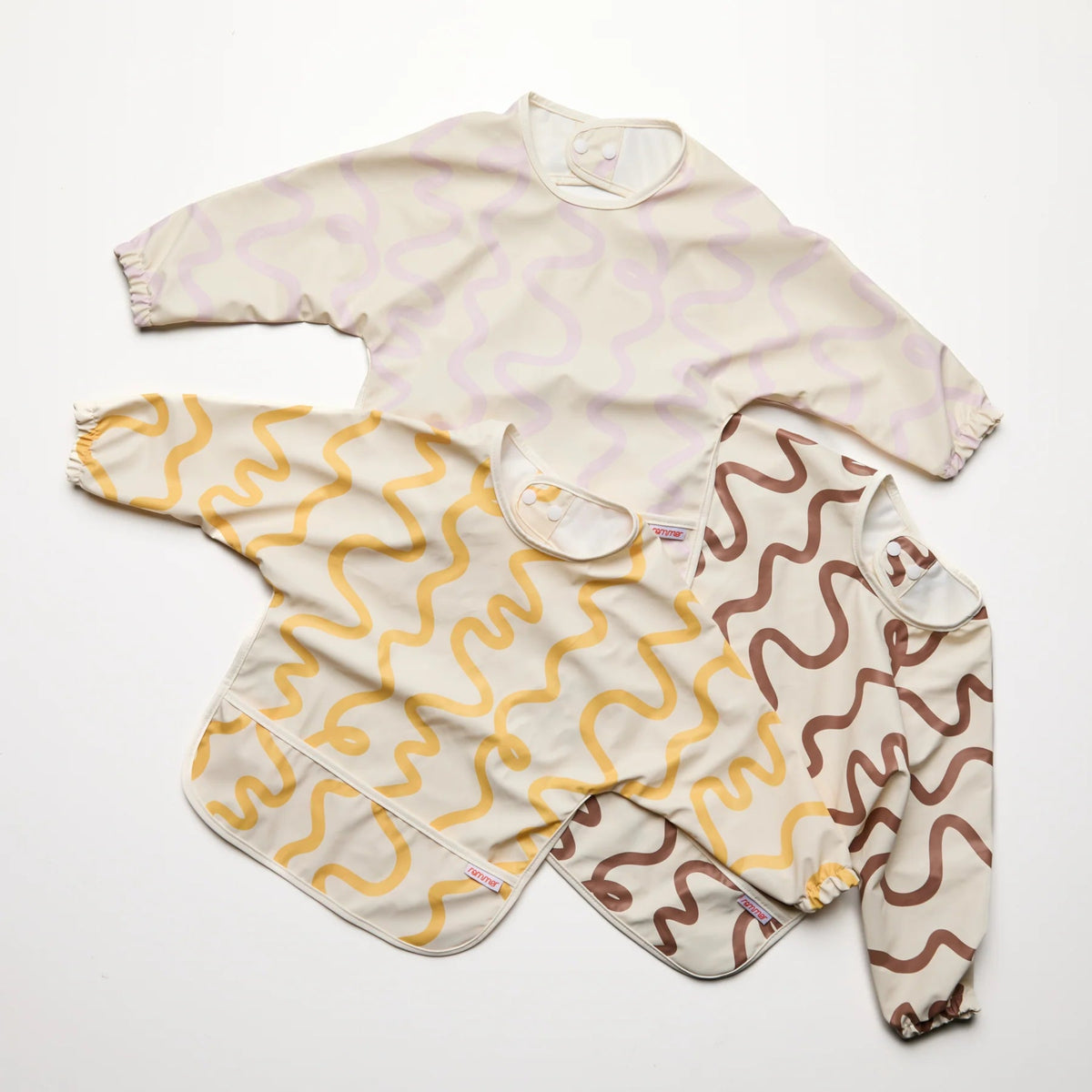 Three Rommer smock bibs with different wavy pattern designs on a white background